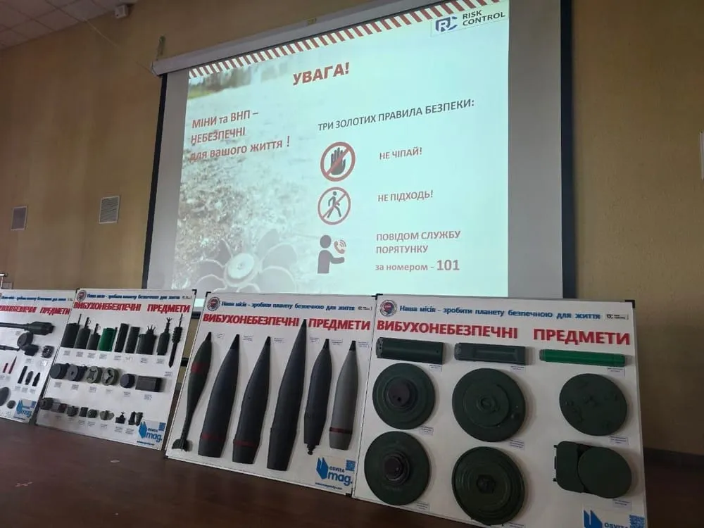 Службовий пес на сцені біля стендів з макетами мін та вибухонебезпечних предметів